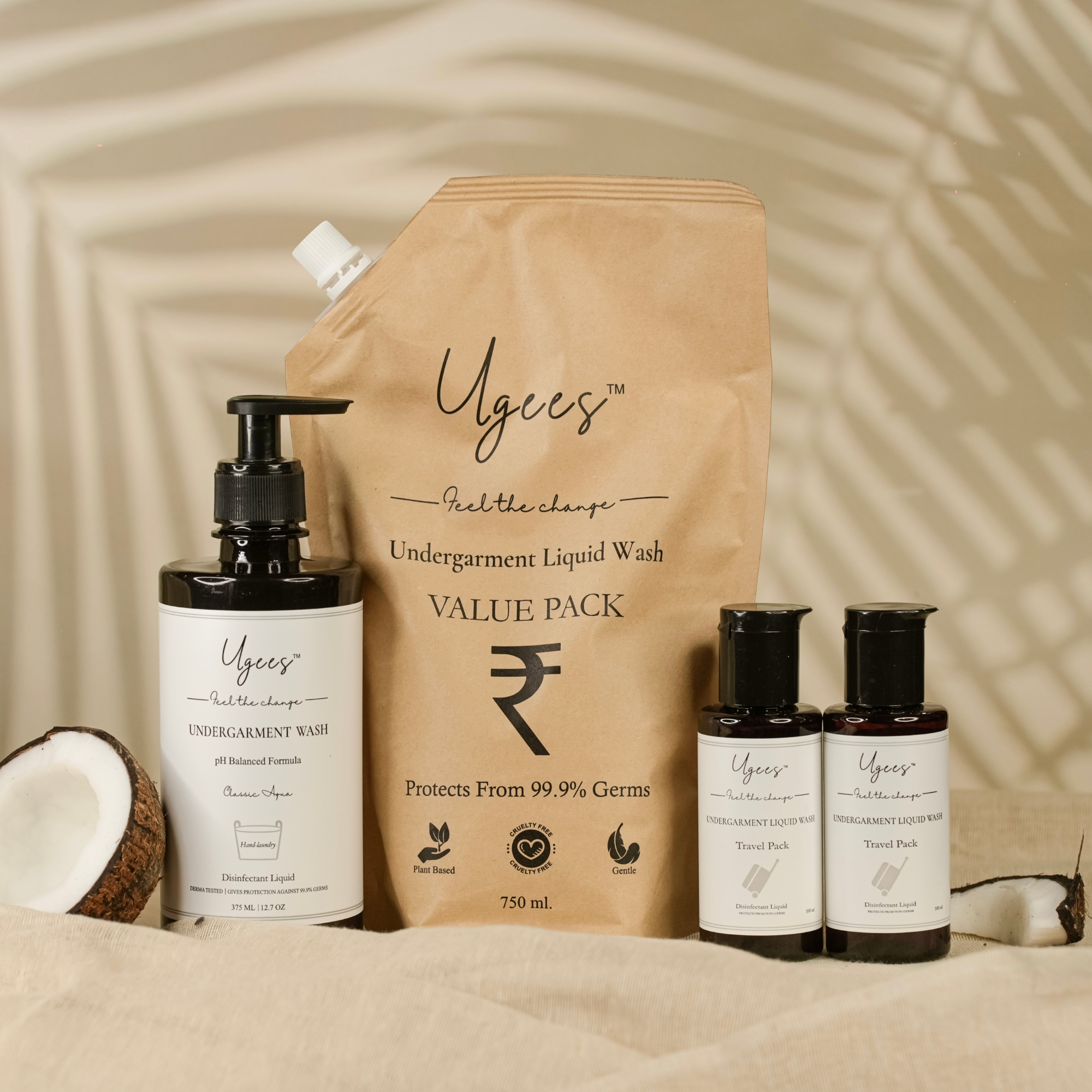 A set of Ugees undergarment hygiene products including a refill pack, a value seller bottle, and a travel pack displayed alongside a coconut and a palm leaf.