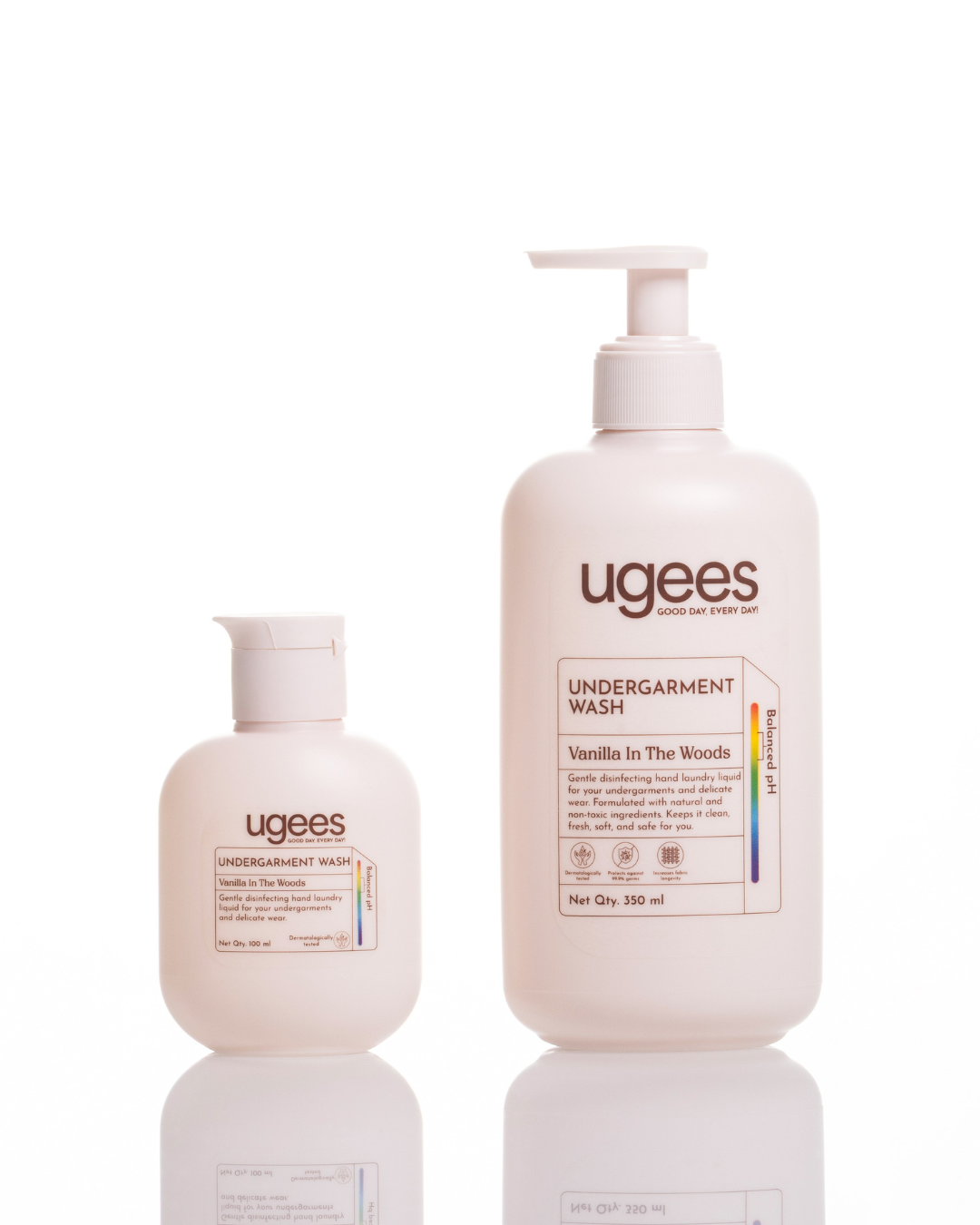 Two Ugees Undergarment Wash bottles on a white reflective background: a smaller pump bottle and a larger squeeze bottle, both in a warm off-white color with brown and black text.